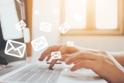 hands on computer keyboard with floating envelopes